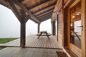 Une terrasse en bois avec une table de pique-nique, un chemin de pierre et un bâtiment en bois doté d’une porte en verre.