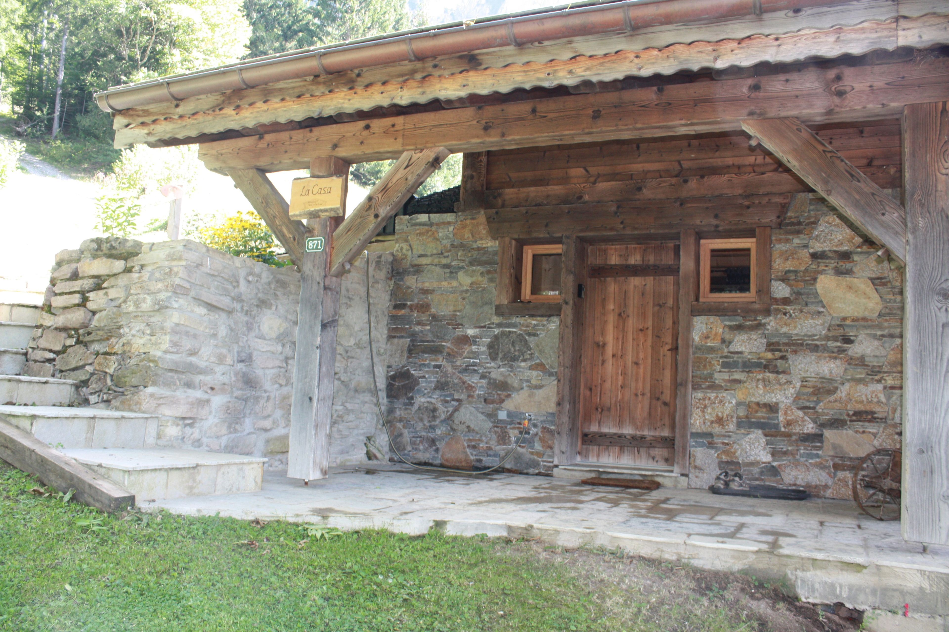 Un edificio rústico de piedra con puerta de madera y un pequeño porche.