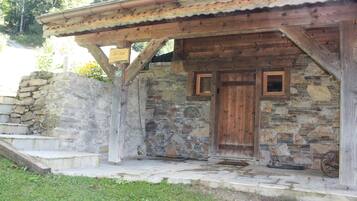 Un edificio rústico de piedra con puerta de madera y un pequeño porche.