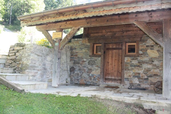 A rustic stone building with a wooden door and a small porch.