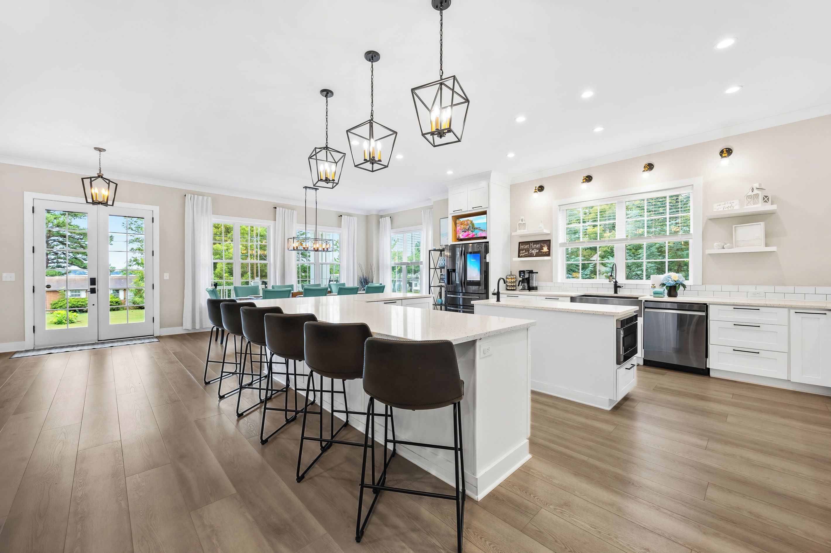 A modern kitchen with a central island, bar stools, a built-in oven, and a large window providing a view of the outdoors.