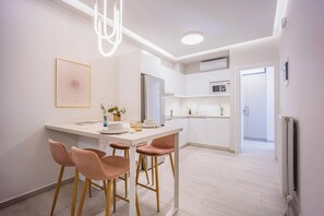 A modern kitchen with white cabinets, a central island with stools, and a pendant light. - FiftySeven Athens - Lemon Garden Hideaway | B3 (Athina)