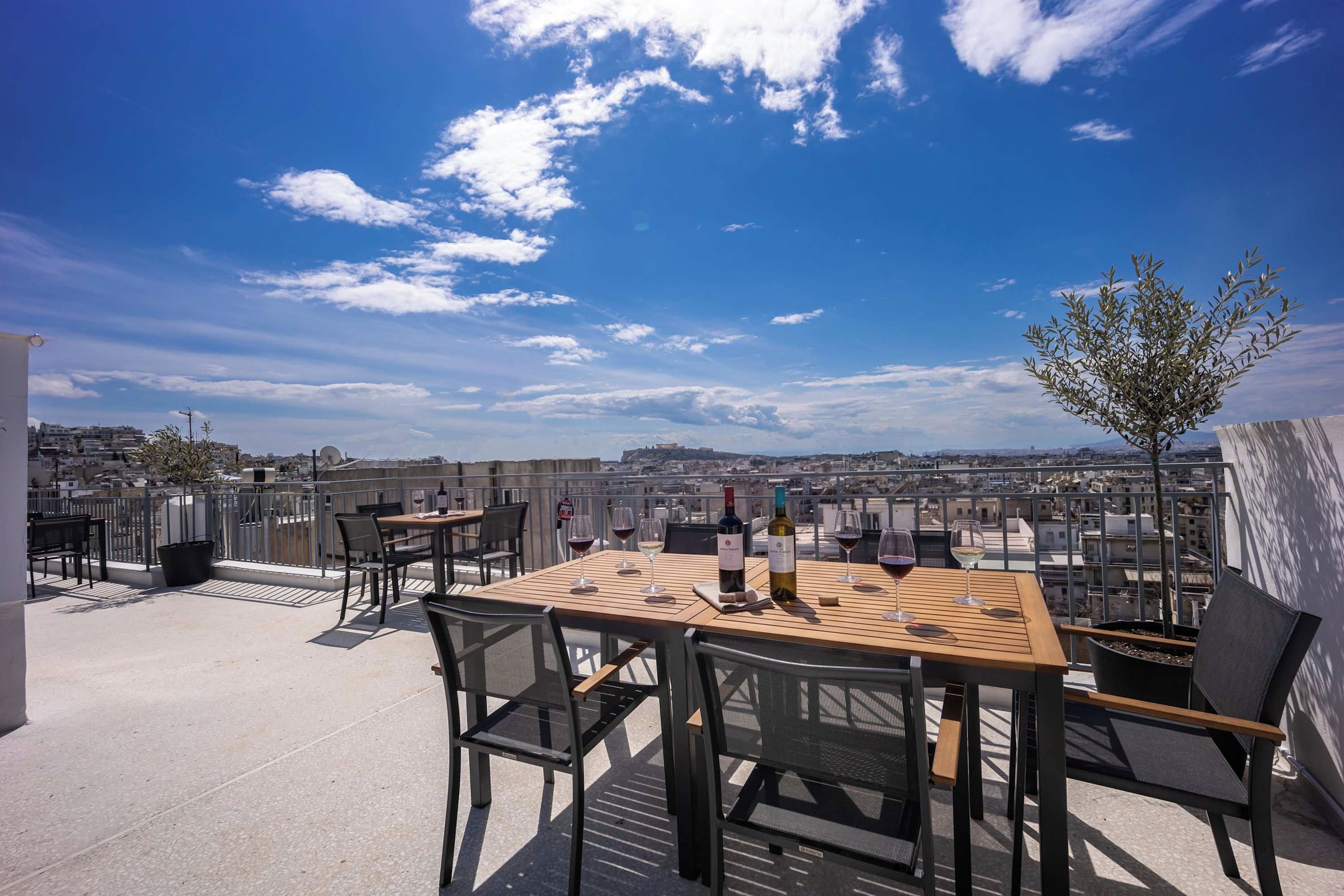 Une terrasse sur le toit, avec une table dressée pour le dîner, une vue sur le paysage urbain et un ciel dégagé.