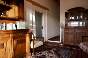 Ein Zimmer mit einem Holzschrank, einem Stuhl, einem gemusterten Teppich und einem Bücherregal.
