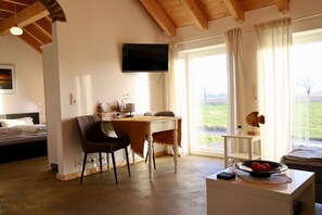 Ein Zimmer mit einem Bett, einem Schreibtisch mit Stuhl, einem an der Wand befestigten Fernseher und einem Fenster mit Vorhängen.