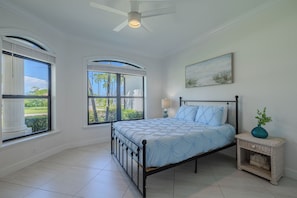 A bedroom with a bed, a nightstand, a lamp, and two windows. - Hot tub and pool, garage the best games, sleeps up to 8! (Cape Coral)