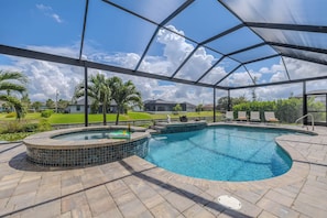 A swimming pool with a hot tub, surrounded by a covered patio area. - Hot tub and pool, garage the best games, sleeps up to 8! (Cape Coral)