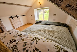 A bedroom with a bed, a window, and a door.