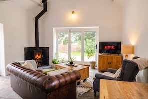 A living room with a fireplace, leather sofa, wooden coffee table, and a TV displaying 'NETFLIX'.