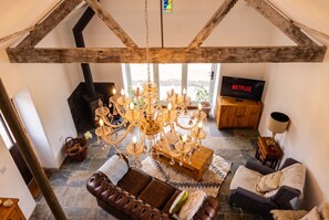 Seen from the mezzanine, the chandelier hangs over the lounge and stove below. - Log-Burner Barn for 4 · Free Parking · Walk to Sea, Blue Anchor (Blue Anchor)