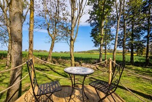 An outdoor seating area with a round table and two chairs, surrounded by trees and a grassy field. - Dog-Friendly Glamping Dome for 4 · Private Copse · Walk to Blue Anchor Beach (Blue Anchor)