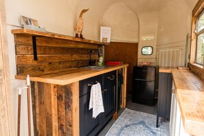 Une cuisine de taille réduite, dotée d’un plan de travail en bois, de meubles de rangement noirs et d’une petite fenêtre.