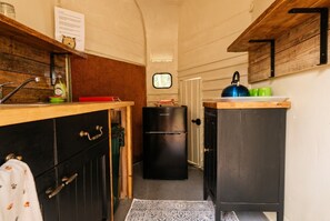 A compact kitchen with a black refrigerator, wooden cabinets, and a window. - Dog-Friendly Glamping Dome for 4 · Private Copse · Walk to Blue Anchor Beach (Blue Anchor)