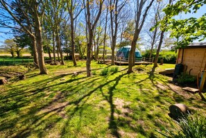 A campsite with a tent, wooden structures, and a fenced area. - Dog-Friendly Glamping Dome for 4 · Private Copse · Walk to Blue Anchor Beach (Blue Anchor)