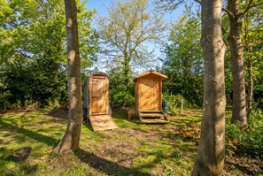Deux constructions en bois, l’une dotée d’une porte et d’une rampe, et l’autre d’une porte et d’un escalier, sont entourées d’arbres.