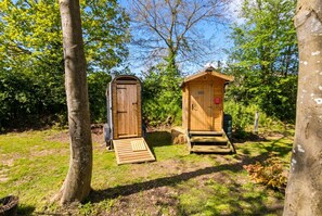 Two wooden structures with doors and steps, surrounded by trees and grass. - Dog-Friendly Glamping Dome for 4 · Private Copse · Walk to Blue Anchor Beach (Blue Anchor)