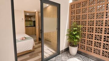A room with a bed, a sliding door leading to a kitchen, and a decorative wooden partition.