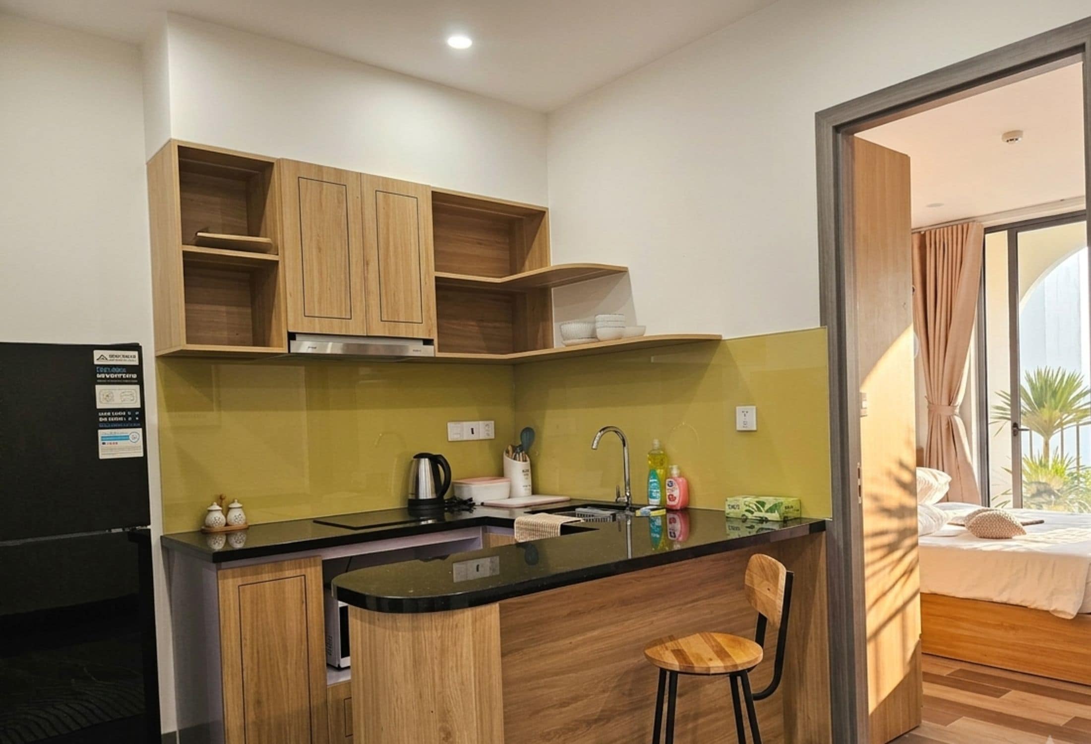 A compact kitchen with wooden cabinets, a black countertop, and a small bar area.