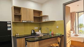 A compact kitchen with wooden cabinets, a black countertop, and a small bar area.