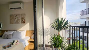 A hotel room with a bed, bedside table, and a potted plant.