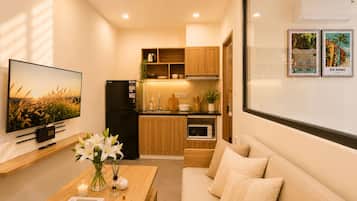 A compact kitchen with wooden cabinets, a black refrigerator, and a microwave.