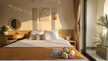 Una habitación de hotel con cama, mesita de noche, espejo, decoración en la pared y una ventana con cortinas.