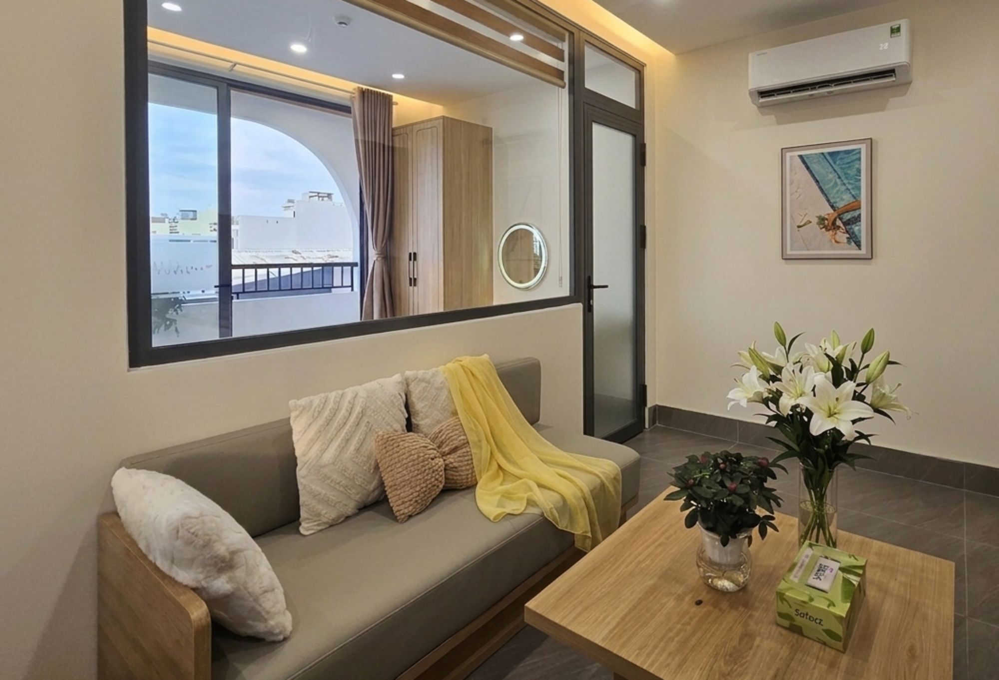 Sala moderna com sofá, mesa de centro e janela com vista para edifícios.