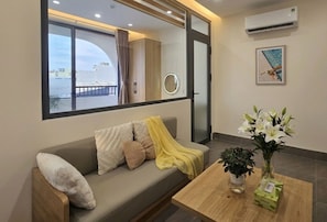 Sala moderna com sofá, mesa de centro e janela com vista para edifícios.
