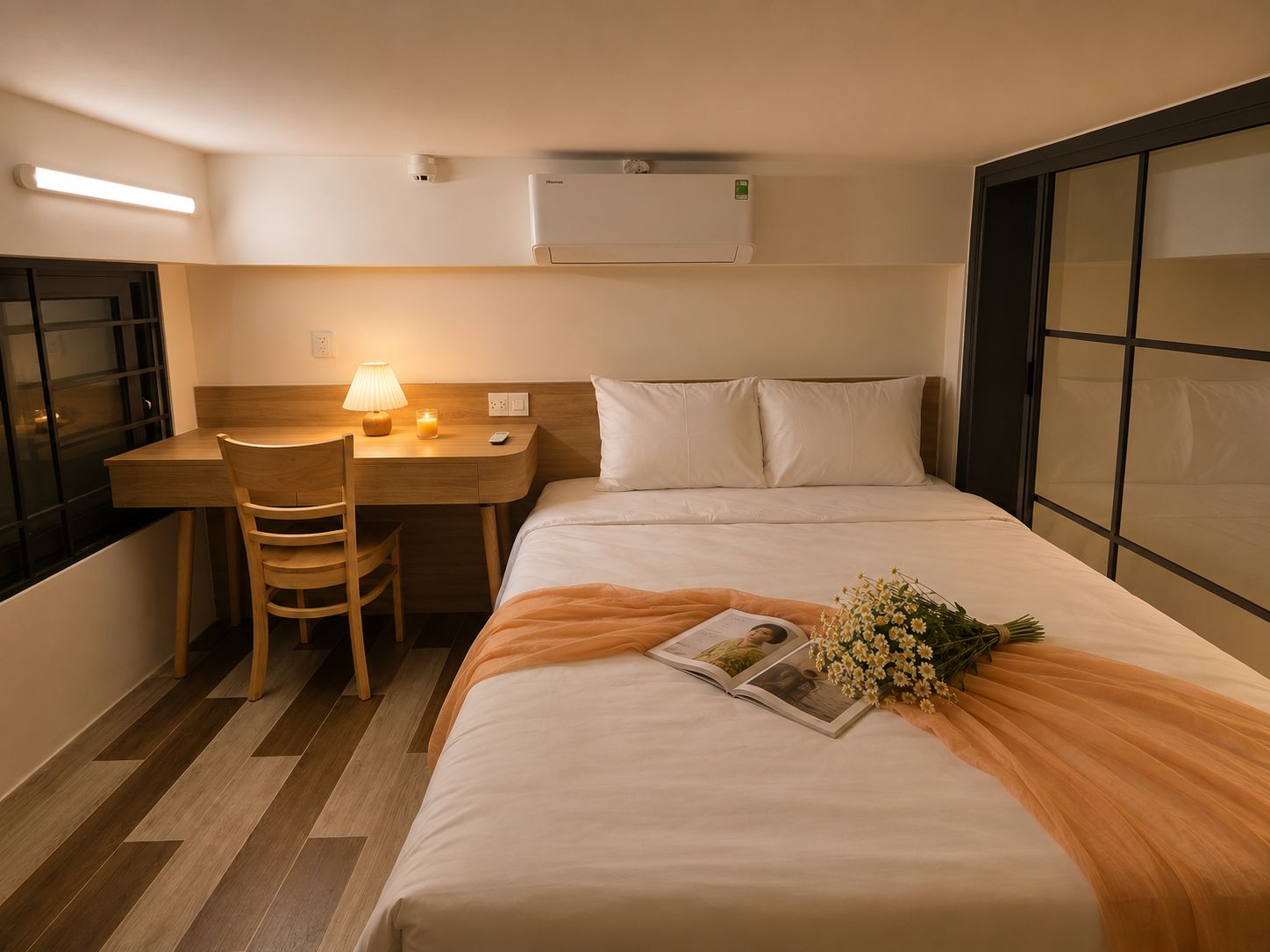 A hotel room with a bed, a desk, a chair, a lamp, and a window.