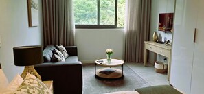A living room with a sofa, a round coffee table, a lamp, and a window with curtains. - Zimbali Boulevards (Ballito)