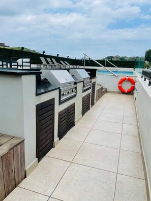An outdoor patio with a barbecue grill, a pool, and a lifebuoy. - Zimbali Boulevards (Ballito)