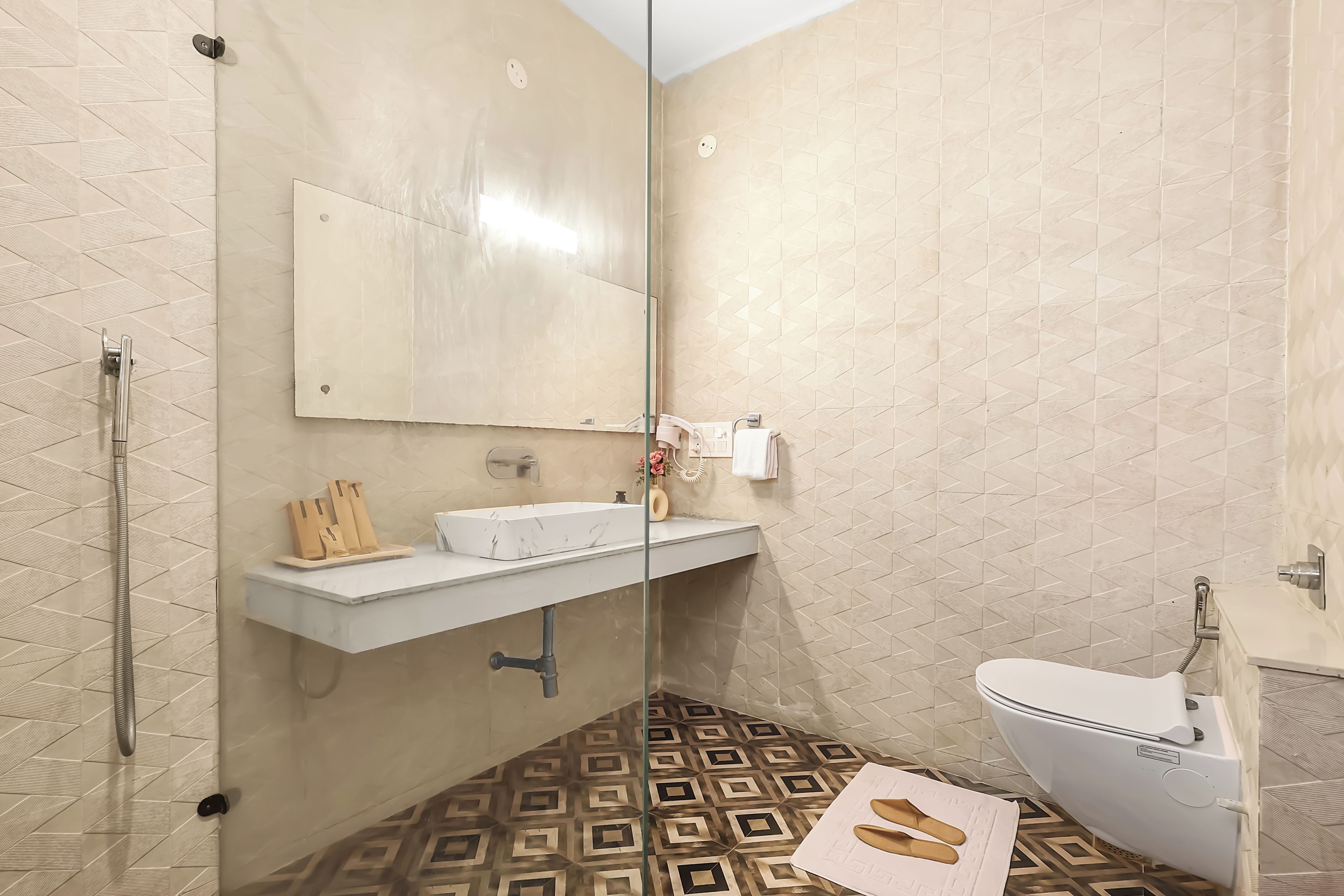 A bathroom with a glass shower enclosure, a white sink, and a toilet.