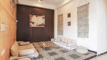 A modern living room with a sofa set, a coffee table, patterned flooring, and decorative wall hangings.