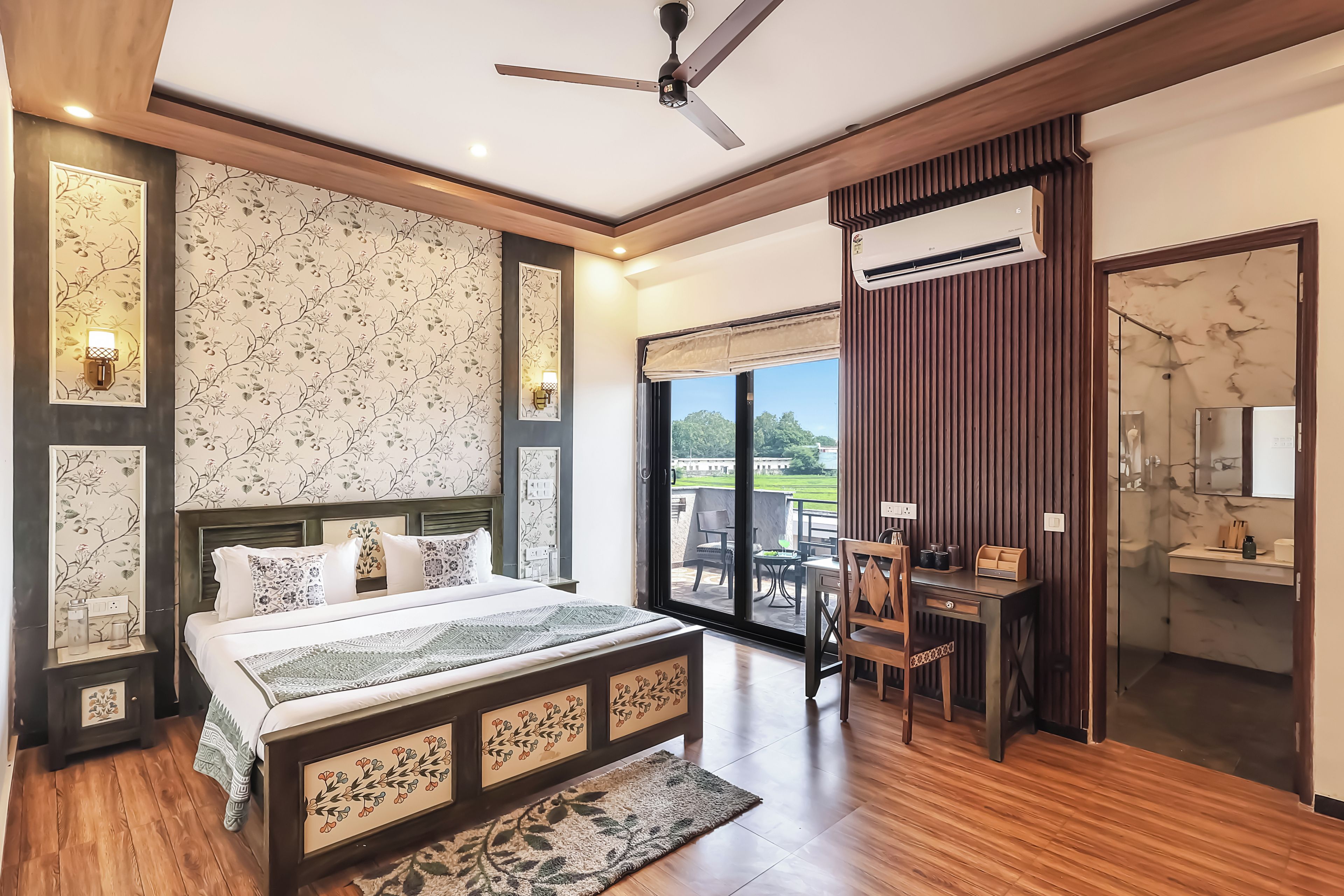 A bedroom with a bed, bedside tables, a desk, and a view of the outdoors.