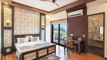 A bedroom with a bed, bedside tables, a desk, and a view of the outdoors.