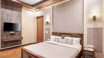 A modern bedroom with a large bed, a flat-screen TV, and a wooden floor.