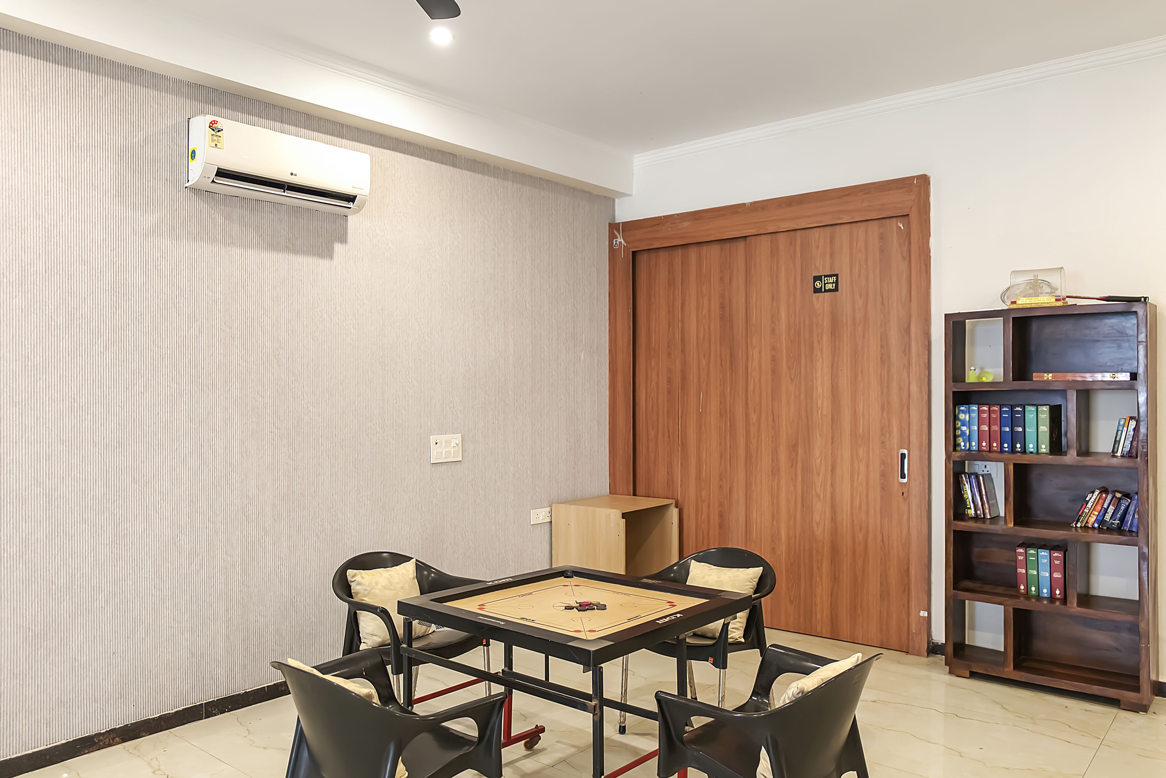 Una habitación con una mesa, sillas, una estantería y una puerta.