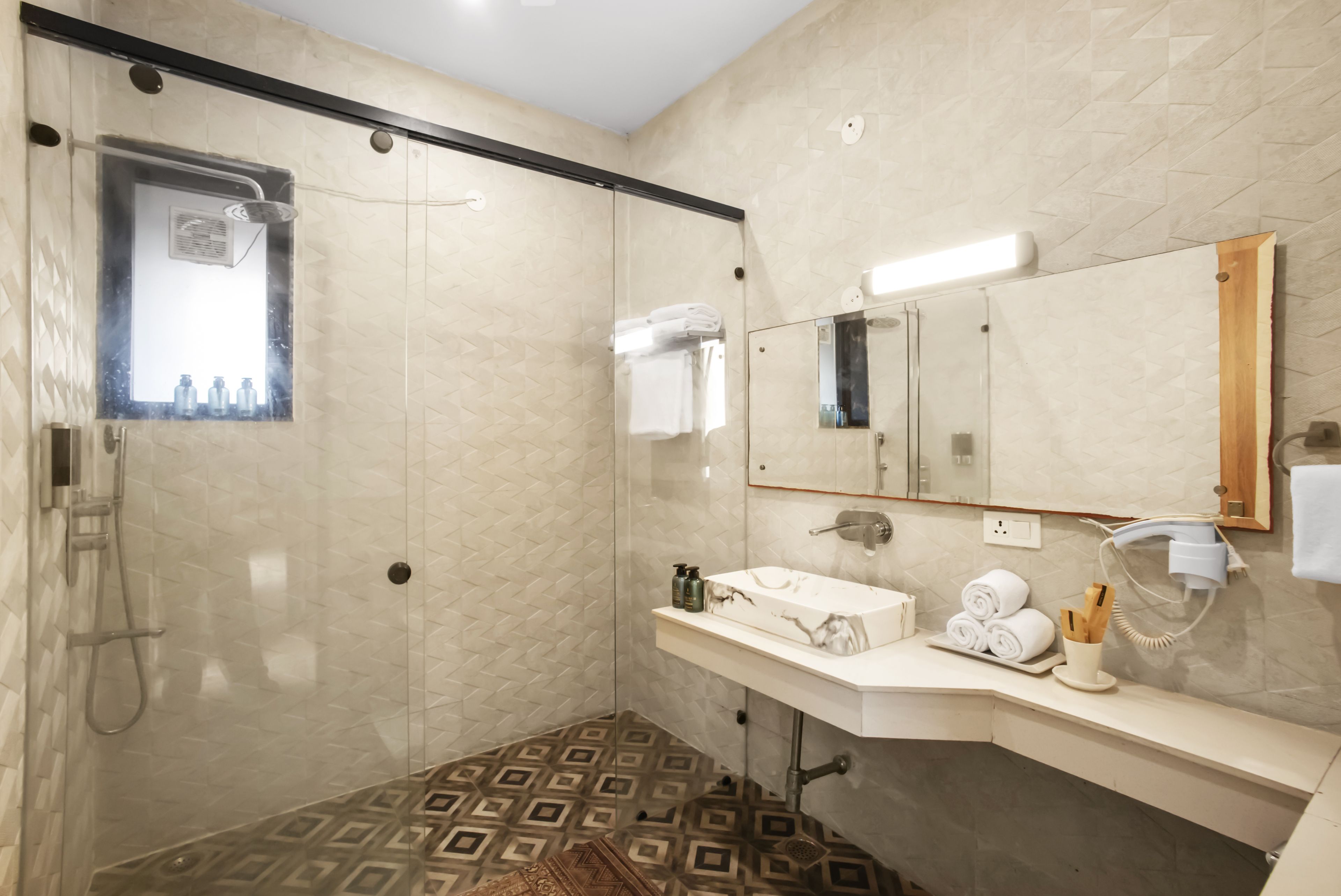 A modern bathroom with a glass-enclosed shower, a vanity with a sink, and a mirror.