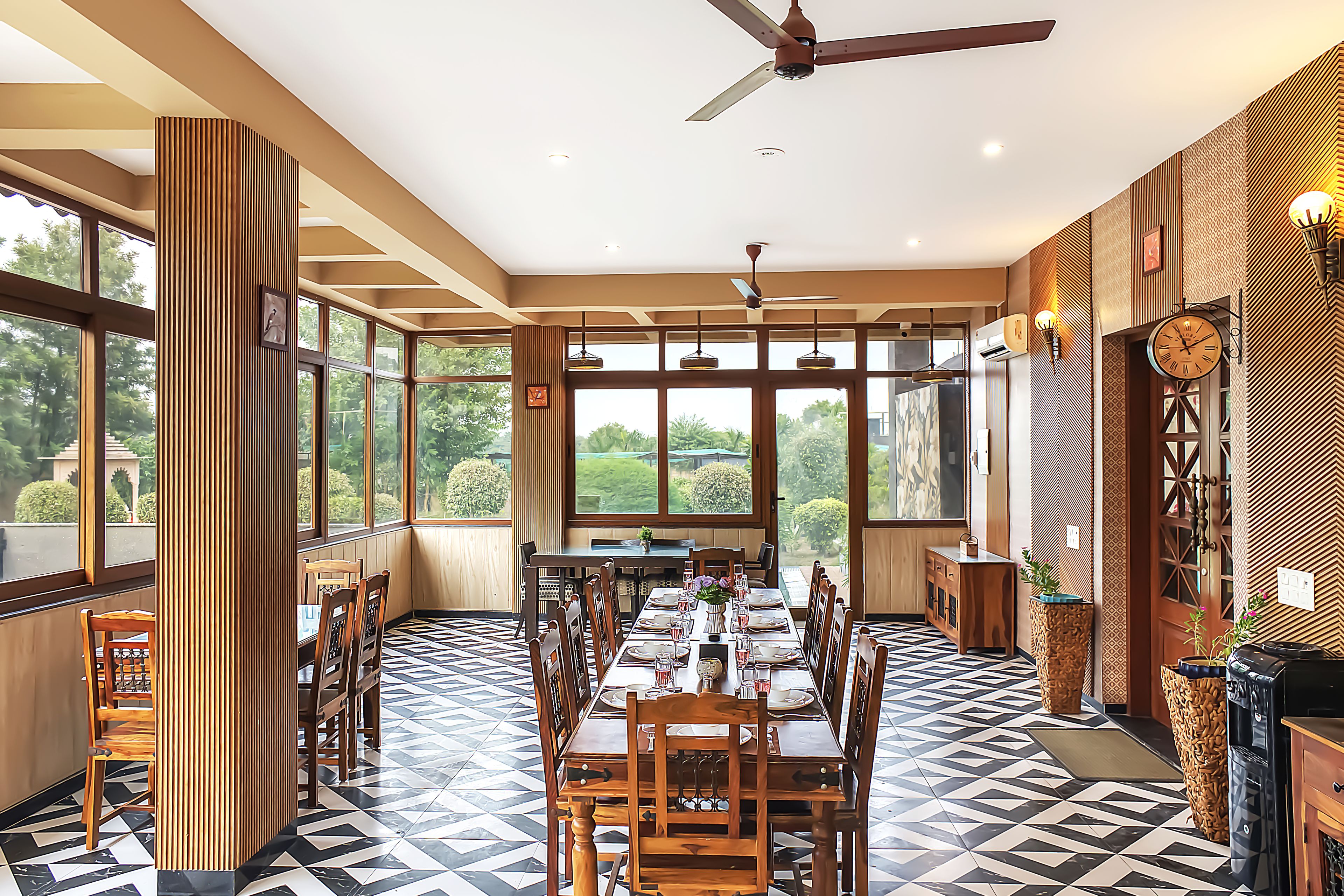 A dining area with a high ceiling, large windows, and a modern chandelier.