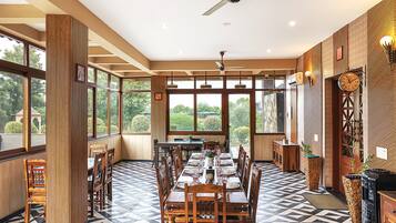 A dining area with a high ceiling, large windows, and a modern chandelier.