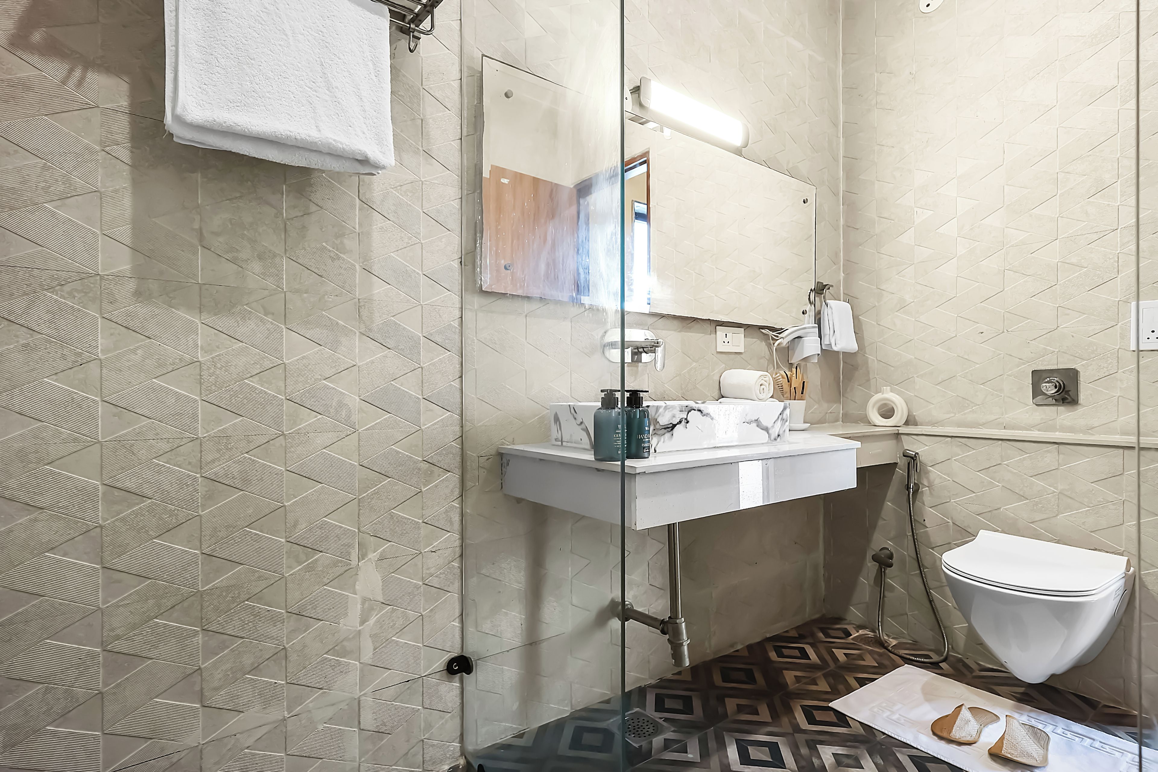A bathroom with a glass shower enclosure, a white sink, and a toilet.
