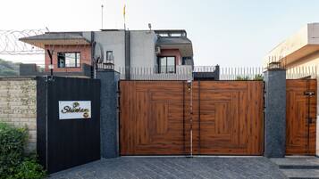 A gated entrance with a sign, a modern building with a flat roof, and a clear sky.