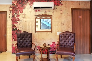 A room with two leather armchairs, a small table, and a wall-mounted air conditioner.