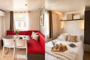 Een kamer met een rode bank, een eettafel met stoelen en een bed met een dienblad vol ontbijtartikelen.