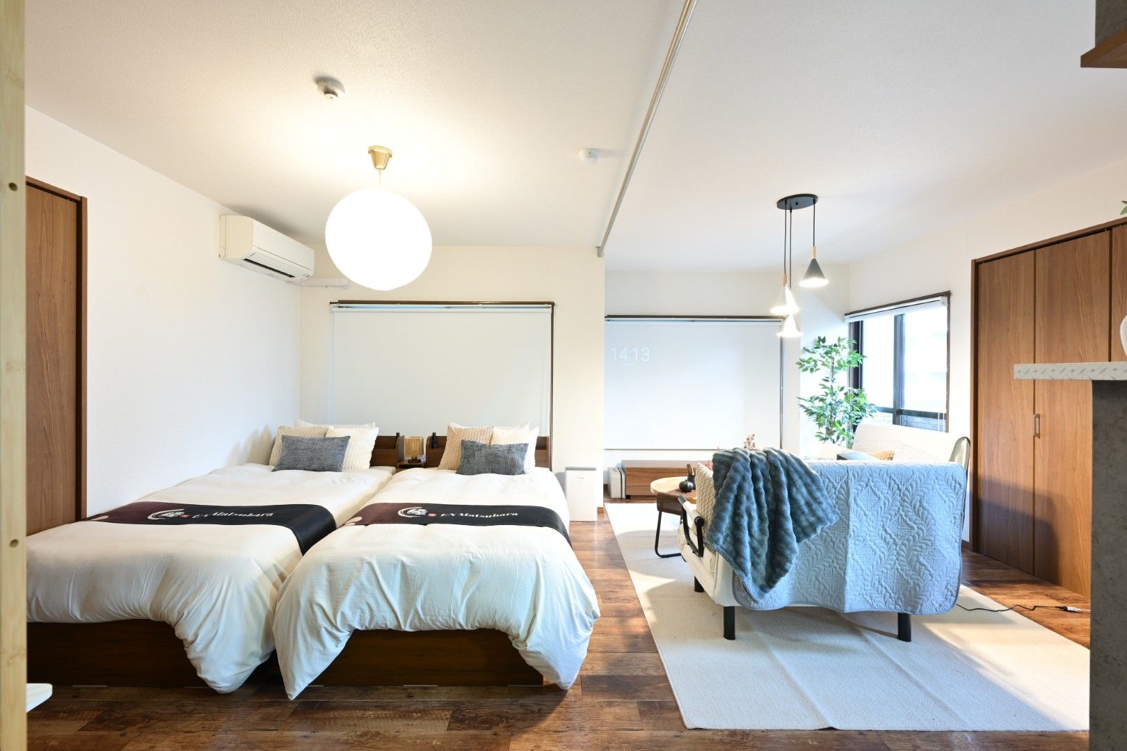 Ein modernes Hotelzimmer mit zwei Betten, einem Schreibtisch und einem großen Fenster.