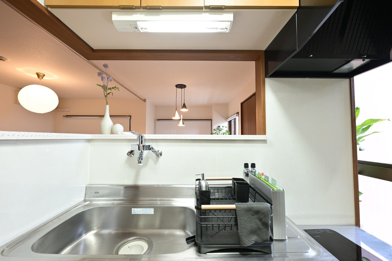A modern kitchen with a stainless steel sink, a dish rack, and a clock on the wall.