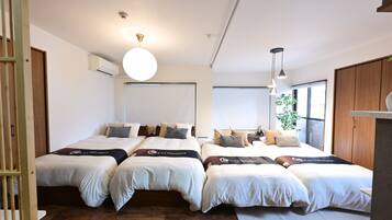 A hotel room with two beds, a large window, and a ceiling light.