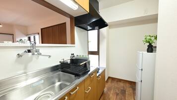 Una cocina con un lavaplatos de acero inoxidable, armarios de madera, una campana extractora negra y un refrigerador blanco.