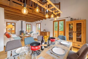 A dining area with a wooden table set for four, surrounded by modern chairs. - Luxury Swiss Alpine Chalet for 10 with Mountain Views minutes to the Gondola (Riddes)