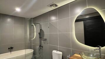 A modern bathroom with a freestanding bathtub, a toilet, and a glass bowl sink.
